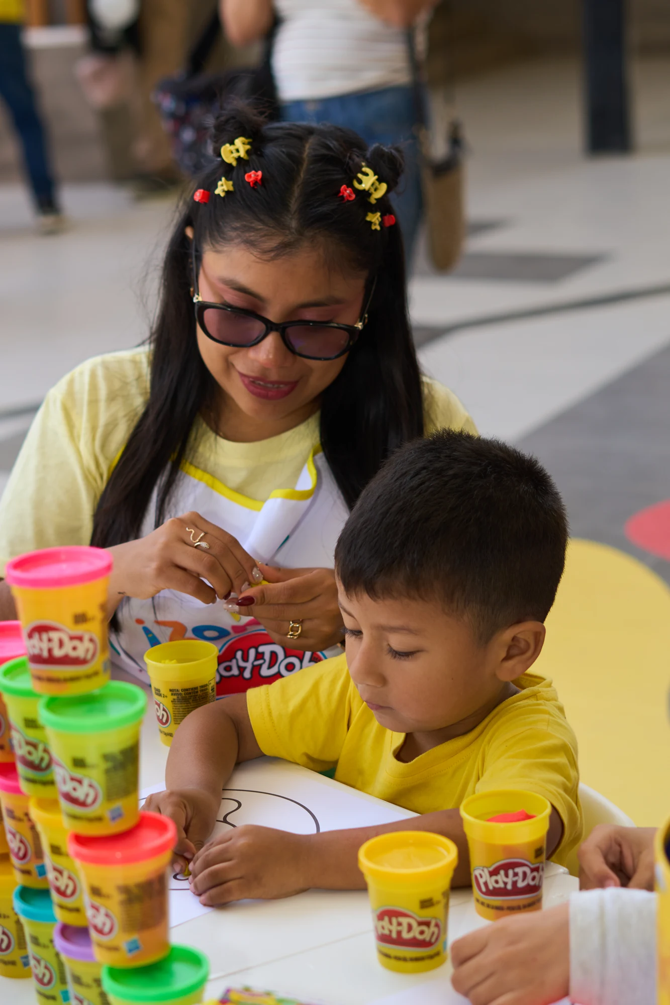Niño creando con plastilina y el acompañamiento de una profesora